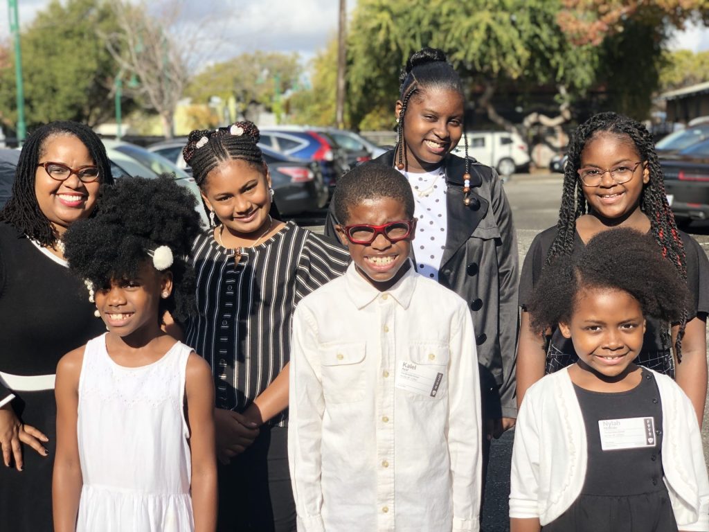 Group of smiling children and women outdoors.