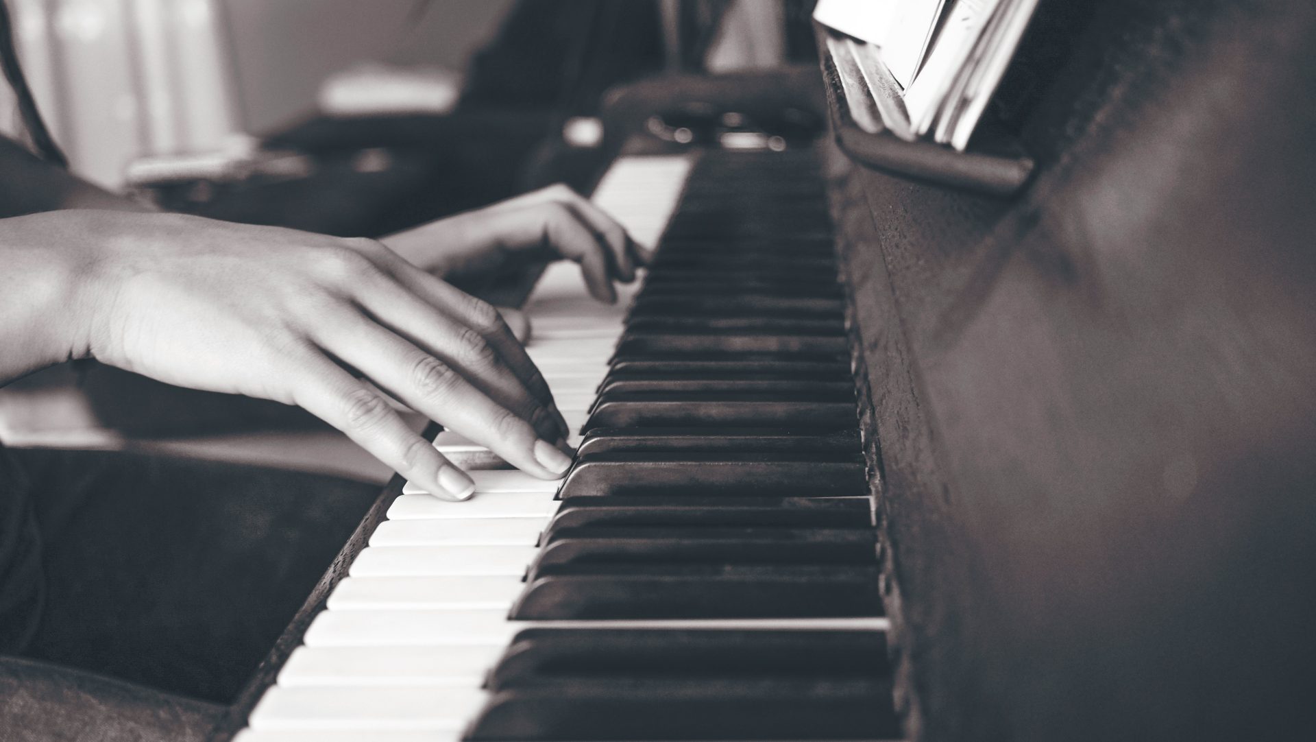 Hands playing a piano in black and white