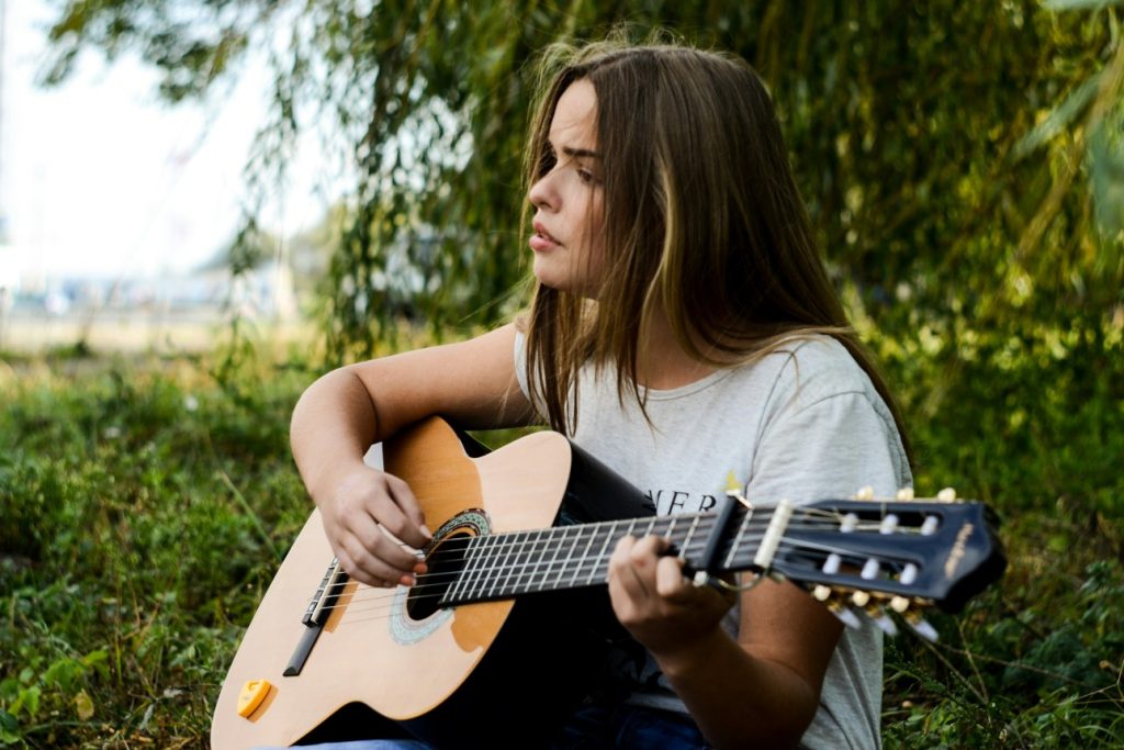 Woman playing acoustic guitar in nature.