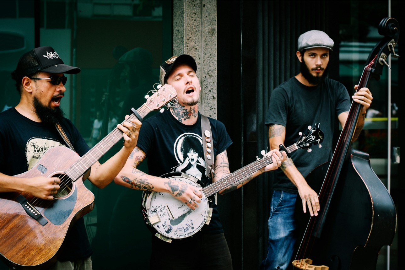 Three musicians performing outdoors with instruments.