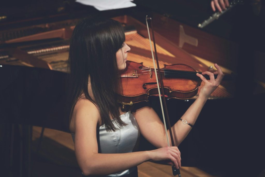 Woman playing violin on concert stage.