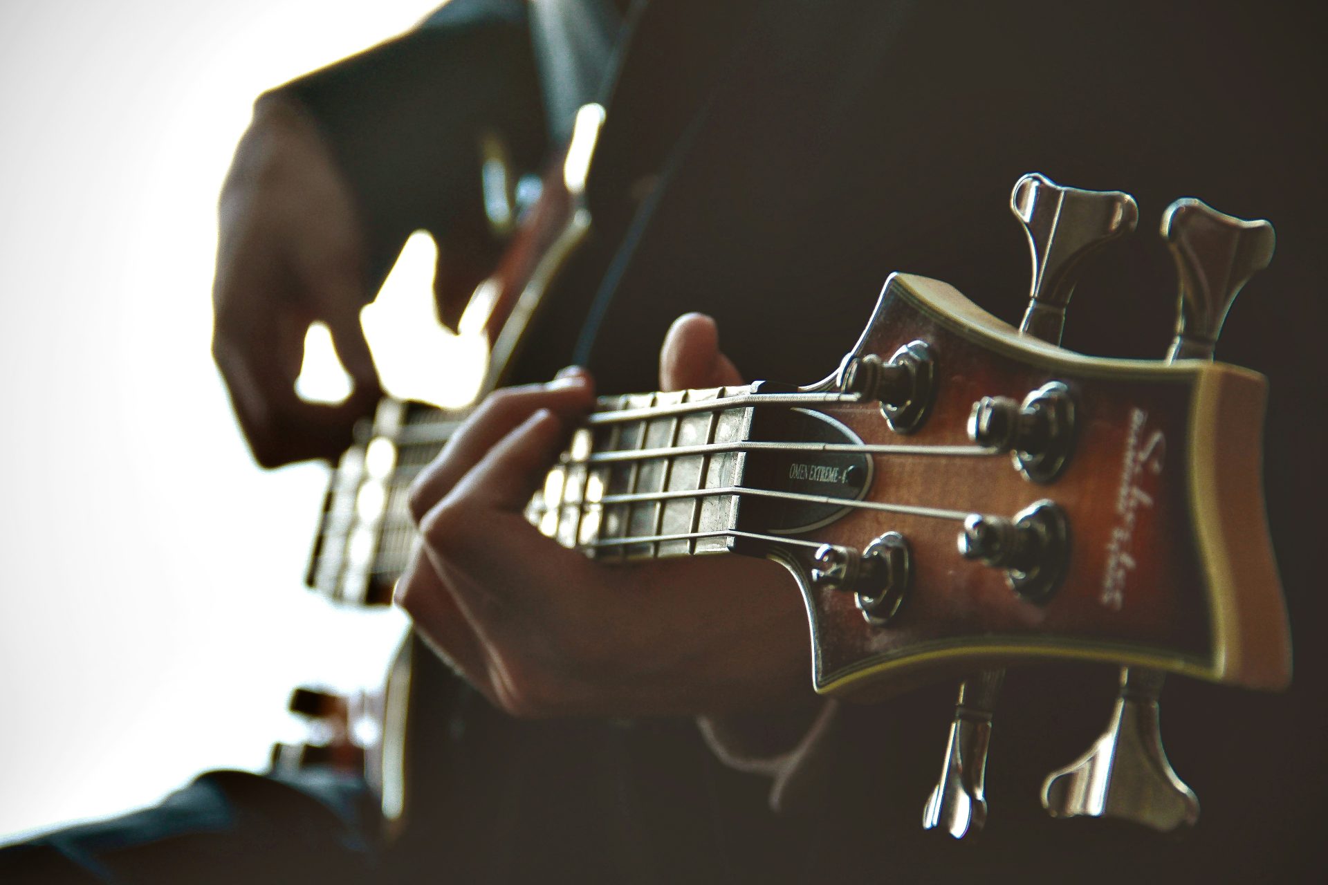 Hands playing a bass guitar, close-up.